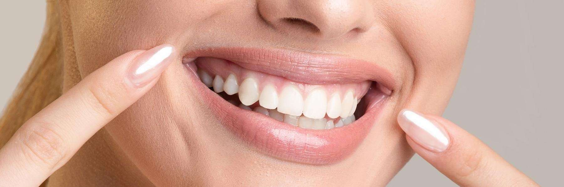 woman pointing at her white teeth
