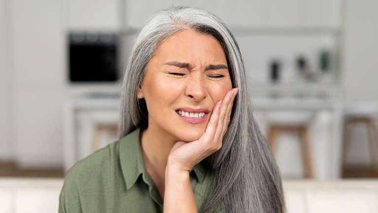 Woman in a dental pain holding her left cheek