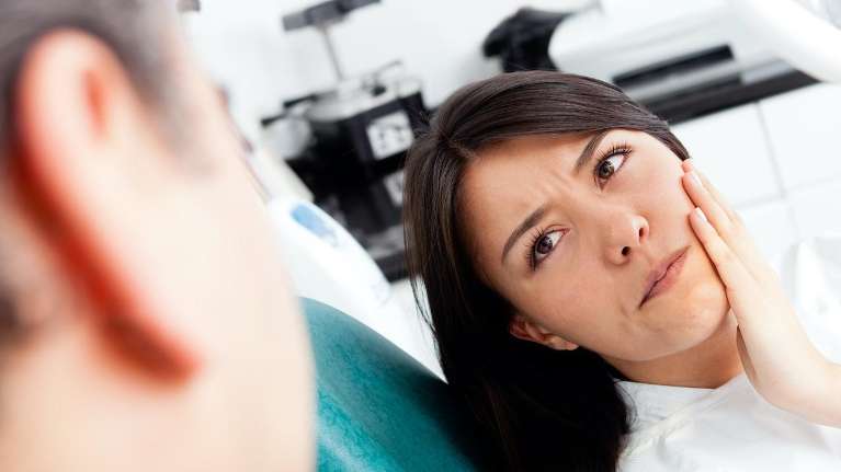 woman holding her left cheek while in pain